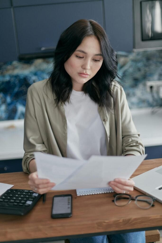 A young woman attentively reviewing documents at home, symbolizing productivity and focus.